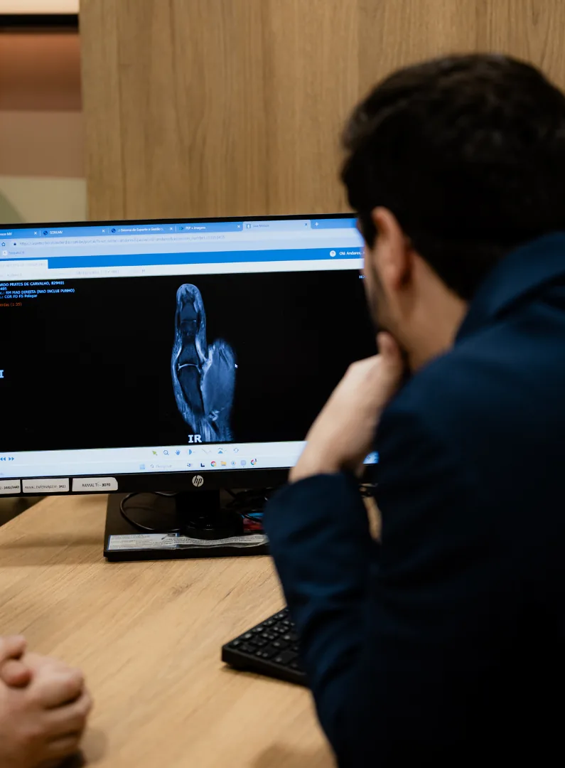 Dr. Henrique Cembranelli analisando exame de imagem do punho no computador